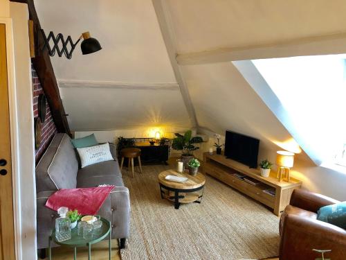 uma sala de estar com um sofá e uma televisão em Lucarne Enchantée em Honfleur