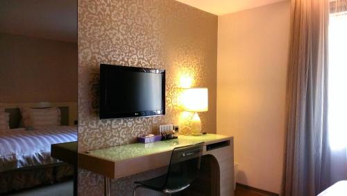 a hotel room with a desk with a tv and a bed at Saual Keh Hotel in Taipei
