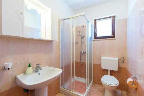 uma casa de banho com um chuveiro, um lavatório e um WC. em Apartmani Popović em Porec