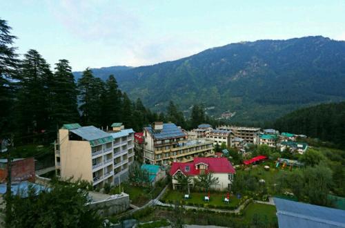 a group of buildings in a city with mountains at Sparsh Resort, A Boutique Stay - Just 2kms uphill from Mall Road, near Old Manali in Manāli