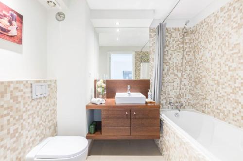 a bathroom with a tub and a toilet and a sink at Amazing Flat - Pool and Parking in Lisbon