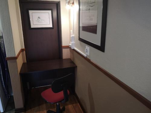 a hallway with a desk and a red chair at De Oude Herberg in Centurion