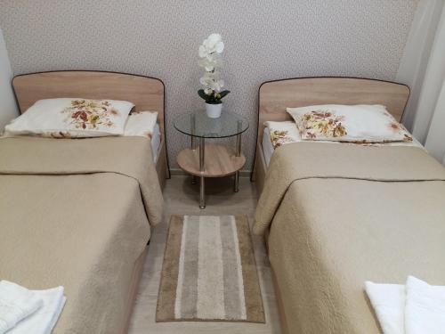 duas camas num quarto com uma mesa entre elas em Butų nuoma Šilutėje em Silutė