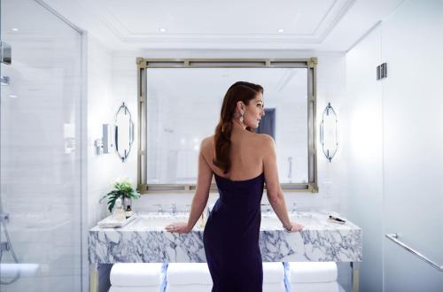 a woman in a black dress standing in a bathroom at Fairmont Royal York Gold Experience in Toronto