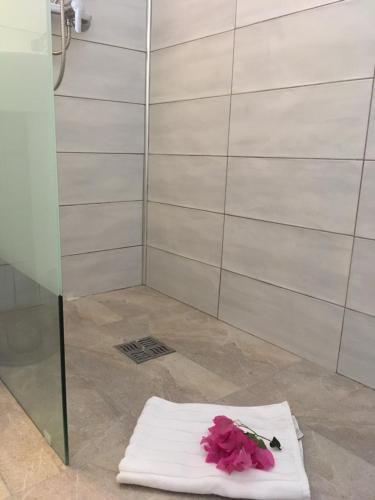 une serviette avec des fleurs roses dessus dans une douche dans l'établissement Studio Bleu Lagon dans résidence avec piscine, au Gosier