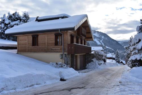 a log cabin in the snow on a snowy road at Chalet le Petit Ramoneur in Châtel