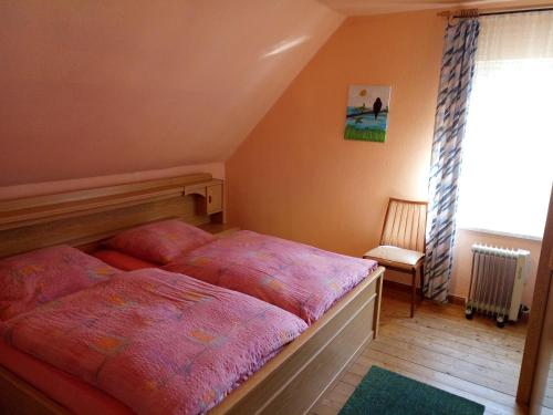 a bedroom with a bed and a chair and a window at Haus Stefanie in Niederburg