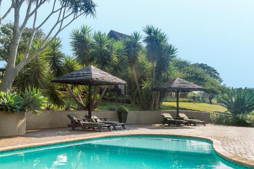 una piscina con sillas y sombrillas junto a un complejo en African Spirit Game Lodge, en Manyoni Private Game Reserve