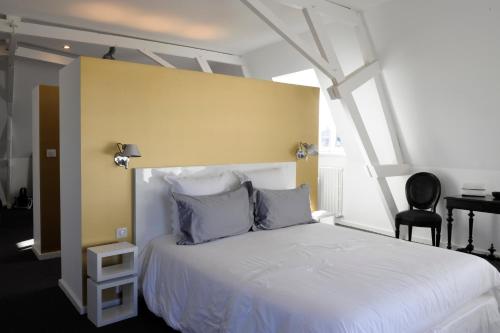 1 dormitorio con cama blanca y pared amarilla en Chambres d'Hôtes Les Tilleuls, en Cognac