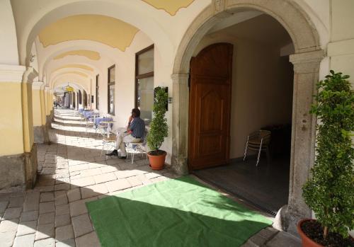a person sitting on a bench in front of a building at Hotel U Černého orla in Telč