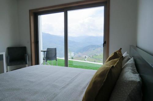 a bedroom with a bed and a large window at Casa Miradouro in Mesão Frio