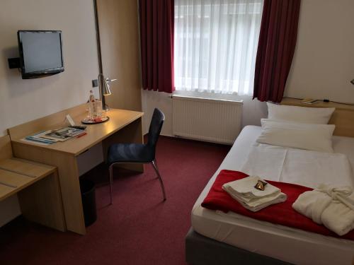 a hotel room with a bed and a desk and a computer at Hotel Haus vom Guten Hirten in Münster