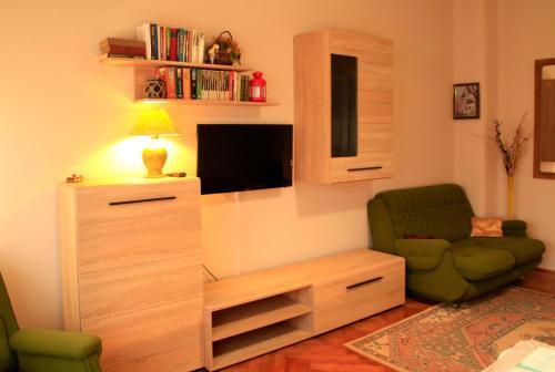 a living room with a television and a green chair at Avar Vendégház in Matrafured