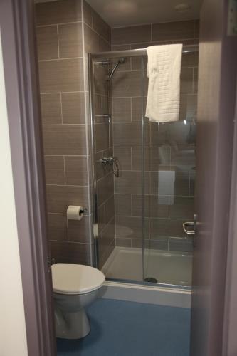 a bathroom with a toilet and a glass shower at Liberal House Tamworth in Tamworth