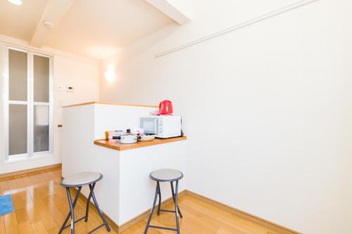 eine Küche mit zwei Hockern und einer Mikrowelle an der Wand in der Unterkunft Haneda Airport Apartment in Tokio