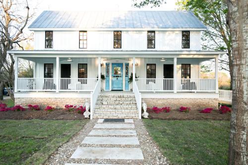 a white house with a blue door and flowers at The Frenchie in Round Top