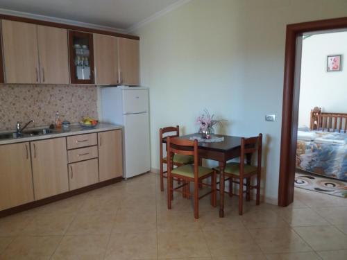 una cucina con tavolo, sedie e frigorifero di Guesthouse Fatos Biti a Divjakë