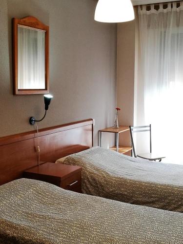 a hotel room with two beds and a mirror at Pension Santiago in Burgos