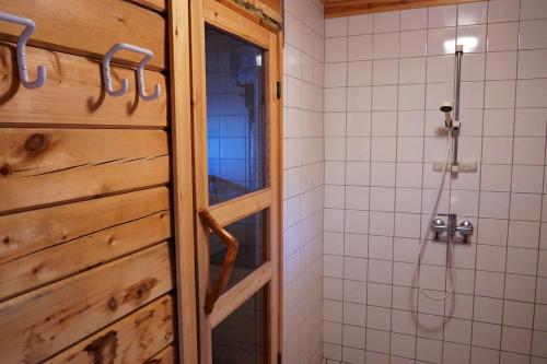 ein Badezimmer mit einer Dusche und einer Holztür in der Unterkunft Stenstrandintie 20 B in Jorvas