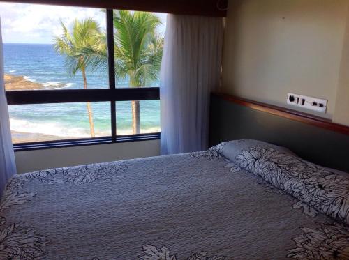a bedroom with a bed with a view of the ocean at Ondina Apart Hotel AP in Salvador