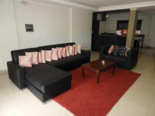 a living room with two black couches and a red rug at Hotel Puesta del Sol by Nobile in Encarnación
