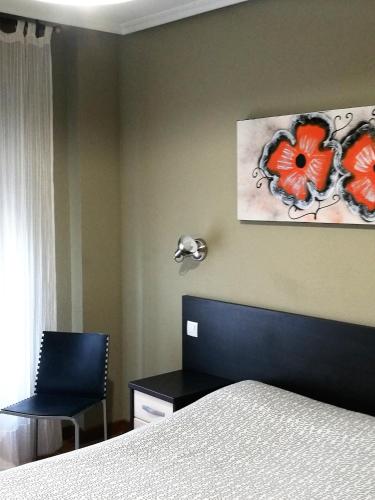a bedroom with a bed and a painting of flowers on the wall at Pension Santiago in Burgos