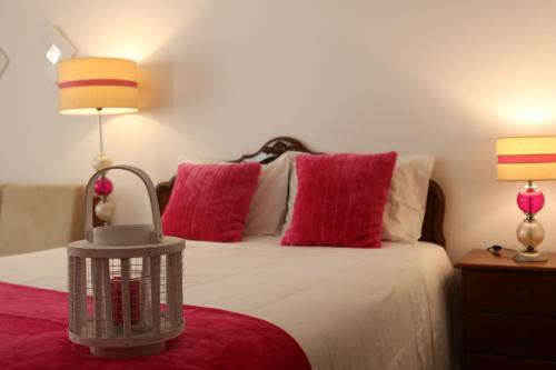 een slaapkamer met een bed met 2 rode kussens bij Solar do Diabrete in Nazaré