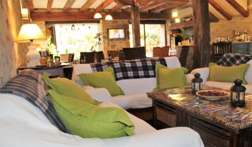a living room with white couches and green pillows at Hotel Rural el Arrabal Siguenza in Sigüenza