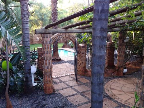 an archway in a garden with a swimming pool at A Knights Rest Guesthouse in Pretoria