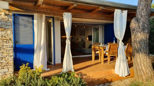 a patio with white curtains and a dining table at Mediterranean Beach House in Umag