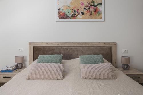 a bed with two pillows and a painting on the wall at Sky Apartments & Rooms in Cavtat