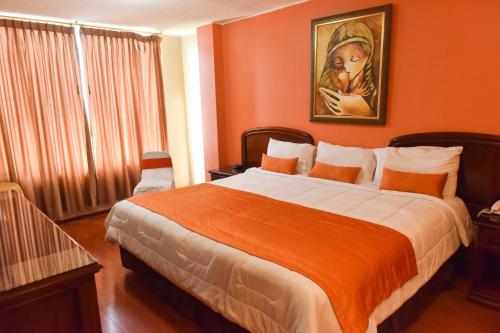 a bedroom with a large bed with orange walls at Hotel Makroz in Latacunga