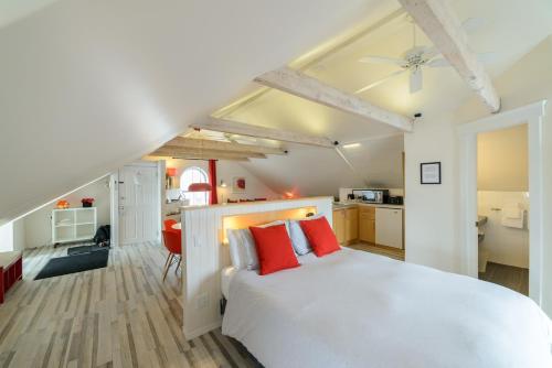 a bedroom with a white bed with red pillows at Auberge aux Deux Lions in Quebec City