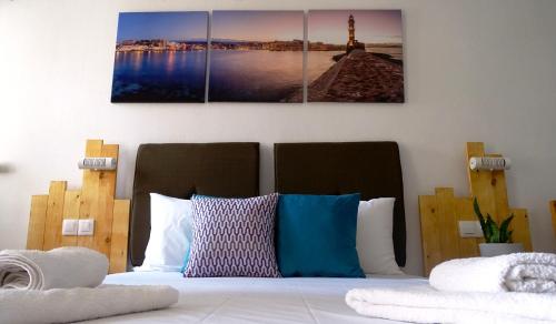a bedroom with a bed with three paintings on the wall at Malia Boutique Studios in Malia