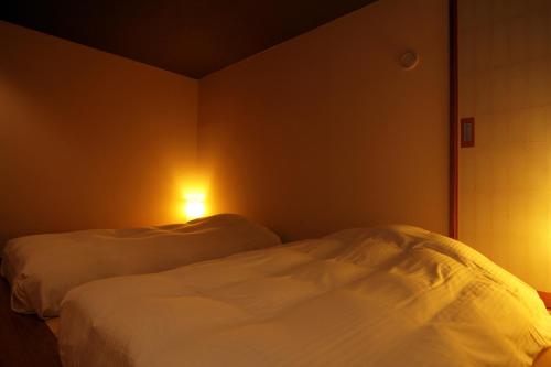 a bedroom with two beds and a light on the wall at Yamado in Nishiwaga