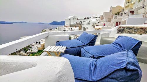 a balcony with blue chairs and a view of the water at Aqua & Terra Traditional Cave Houses in Oia