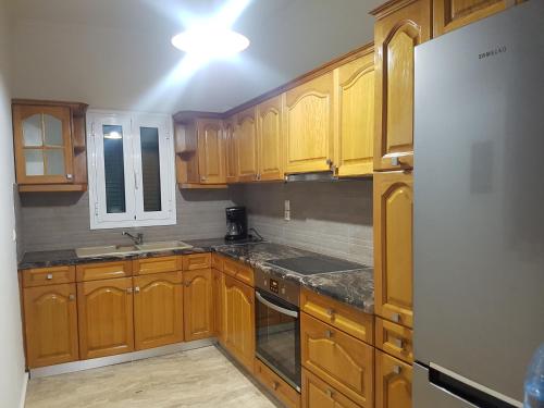 a kitchen with wooden cabinets and a white refrigerator at City Villa -amazing view in Alepou