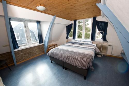 een slaapkamer met een bed in een kamer met ramen bij B&B Molenstraat in Den Burg