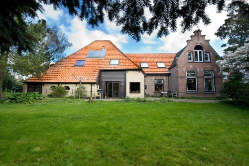 a large brick house with an orange roof at Familiesuite Molenstraat in Den Burg