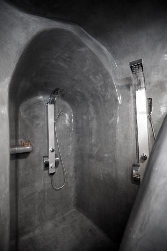 a bathroom with a shower with two lights on the wall at Virginia's Cave Villas in Oia