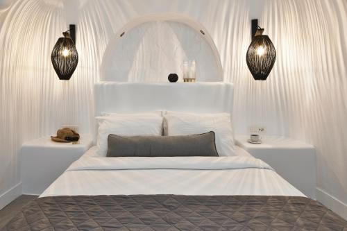 a white bedroom with a large white bed with lights at Virginia's Cave Villas in Oia