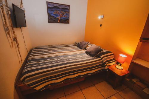 a small bedroom with a bed with a striped blanket at Hostal El Punto in La Serena