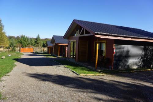 a couple of buildings on a gravel road at Cabañas Cerro Huemules in Coihaique