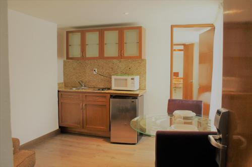 a kitchen with a glass table and a microwave at Condesa Suites in Mexico City