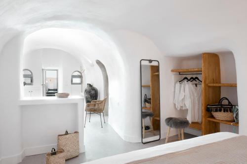 a bedroom with white walls and a bed and a mirror at Virginia's Cave Villas in Oia