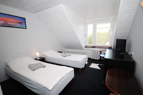 Habitación con 2 camas, escritorio y ventana. en Pensjonat Resident, en Krynica Morska