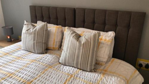 a bed with four pillows on top of it at Nant Apartment - Ground Floor in Menai Bridge