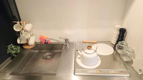 a kitchen counter with a tea kettle on a sink at Casa HANA in Tokyo