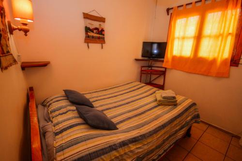 a bedroom with a bed with pillows and a television at Hostal El Punto in La Serena