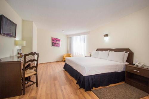 a hotel room with a large bed and a desk at Hotel Valle de Mexico Toreo in Mexico City